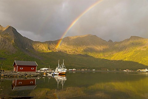 A rainbow over the Norwegian Sea near Grashopen and some fishing boats reflected off the island of Senja, Troms, Norway, Europe