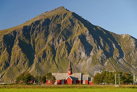 The red stave church of Flakstad in front of steep mountains, Vareid, Fredvang, island of Flakstadoya, Flakstadoya, Lofoten archipelago, Nordland, Norway, Europe