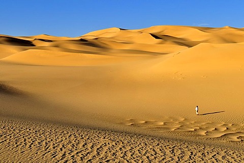 Woman walking on a sand dune near Tehenadou, Adrar n'Ahnet, Algeria, Sahara, North Africa
