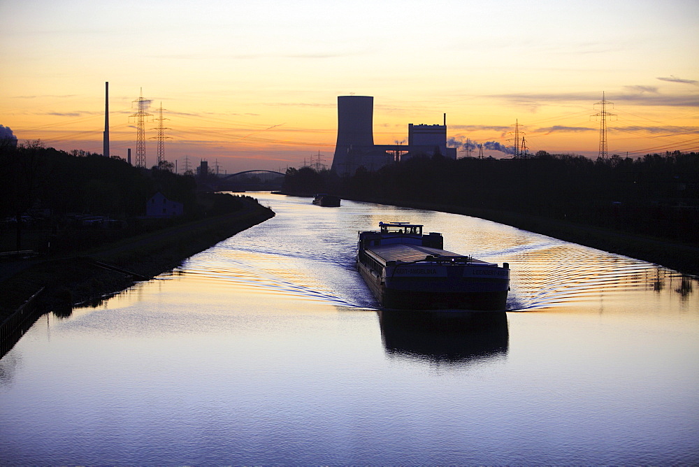 Cargo ship at dawn, Datteln-Hamm-Kanal, canal, near Waltrop, Trianel coal-fired power plant on Stummhafen at back, North Rhine-Westphalia, Germany, Europe