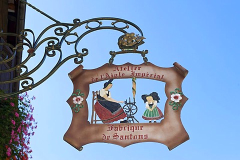 Hanging sign depicting people in typical traditional costume in Kaysersberg, Alsace, France, Europe