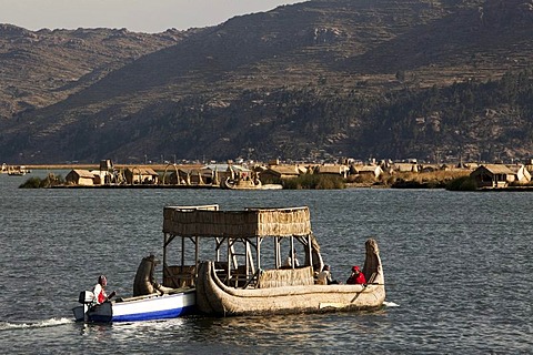 Traditional reed boat being pushed by a motorized boat, floating islands of the Urus on Lake Titicaca, constructed by the totora reeds growing there, Puno, Peru, South America