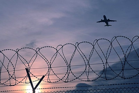 Security fence with an aircraft flying above, Stuttgart airport, Baden-Wuerttemberg, Germany, Europe