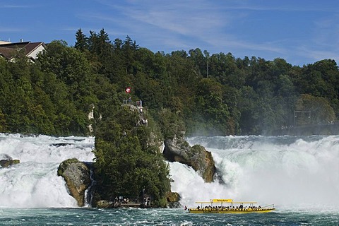 Rock amidst the roaring waters of the Rhine Falls of Schaffhausen, tourist excursion boat at front, Switzerland, Europe