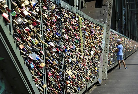 Love padlocks on security grid that separates the footpath from the railway tracks on Hohenzollern Bridge, Cologne, North Rhine-Westphalia, Germany, Europe