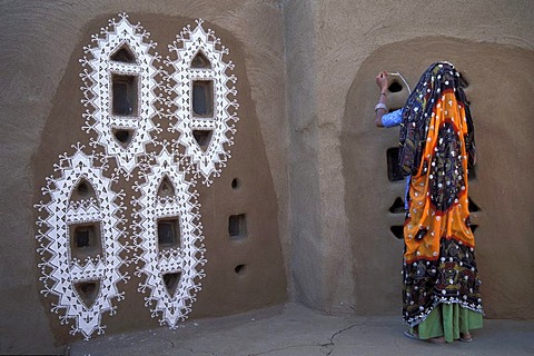 Woman wearing a colorful sari, painting the wall of a mud hut, Mandawa, Rajasthan, northern India, India, Asia