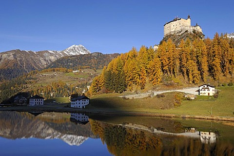 Schloss Tarasp Castle with Lake Tarasp in front of larch forest with autumnal colouring, Tarasp near Scoul, Lower Engadine, Grisons, Switzerland, Europe