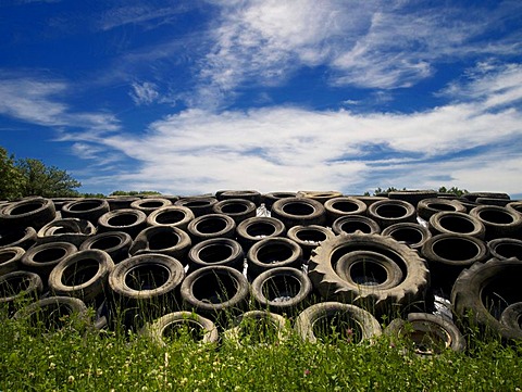 Heap of old tyres on grass, under blue sky