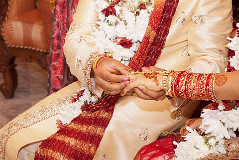 Indian groom passing wedding ring on his bride's finger