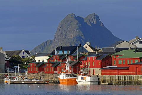 The peaks of VestvÃ‚goy behind the boats and houses of Stamsund illuminated by warm morning light, Nordland, Norway, Europe