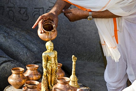 Jain pilgrim is pouring water on the small statue at the feet of the gigantic statue of Gomateshwara in Sravanabelagola, Karnataka, India, Asia