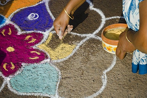 Woman making Rangoli, decorative sand designs in the streets of Madurai during a Hindu festival, meant as sacred welcoming area for the deities, Tamil Nadu, India, Asia