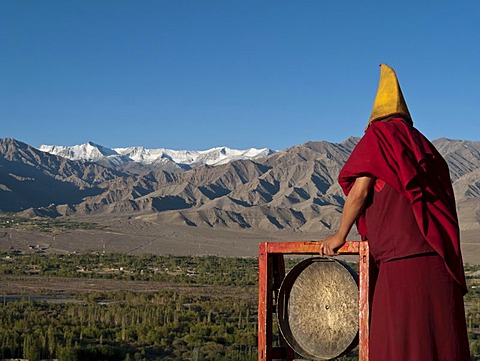 Monk calling for the morning prayers from the rooftop of Thikse Gompa, Thiksey, Jammu and Kashmir, India, Asia