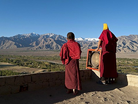 Monks calling for the morning prayers from the rooftop of Thikse Gompa, Thiksey, Jammu and Kashmir, India, Asia