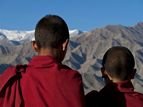 Two young monks looking across the Indus from the rooftop of Thikse Gompa, Thiksey, Jammu and Kashmir, India, Asia