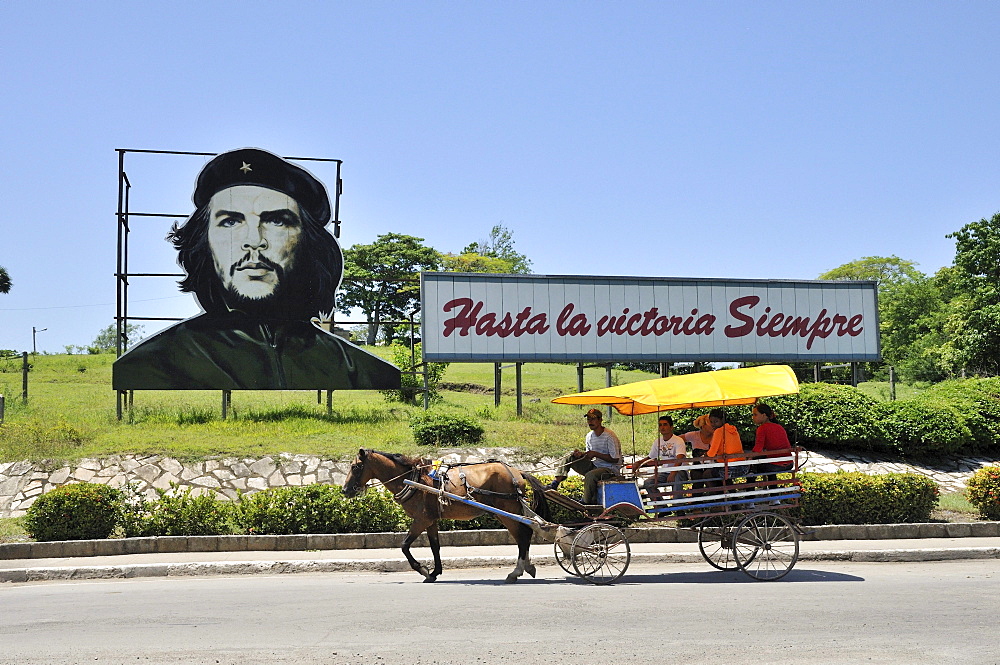 Horse-drawn carriage in front of revolutionary propaganda, "Hasta la victoria siempre", Spanish for "ever onward to victory" with portrait of Ernesto "Che" Guevara, Las Tunas, Cuba, Caribbean