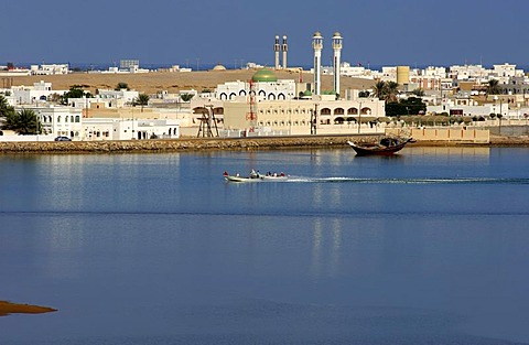 Motor boats on the blue lagoon in front of the white houses of the port city of Sur in the Gulf of Oman, Sultanate of Oman, Middle East