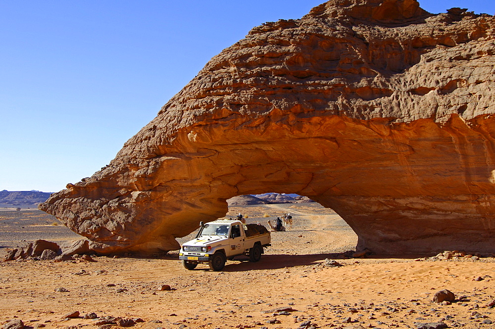 Off-road vehicle driving though a rock arch shaped by wind erosion, Acacus Mountains, Sahara desert, Libya, Africa