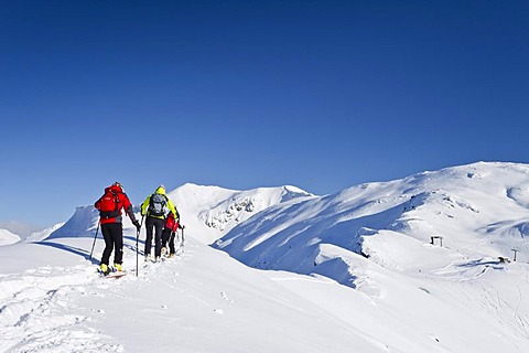 Cross-country skiers on the peak of Morgenrast Mountain above Unterreinswald, Sarntal Valley, looking towards Reinswald ski resort, Alto Adige, Italy, Europe