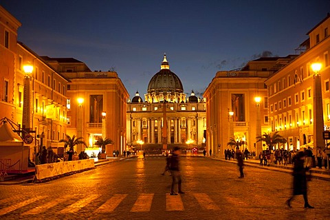 Pedestrians crossing the Via della Conciliazione, road of reconciliation, illuminated St. Peter's Basilica at back, Rome, Italy, Europe