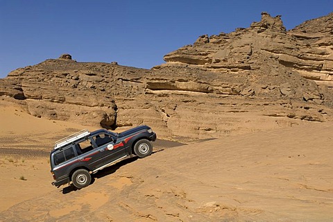 SUV climbing rock, Akakus, Acacus Mountains or Tadrart Acacus, Sahara desert, Fezzan, Libya, North Africa