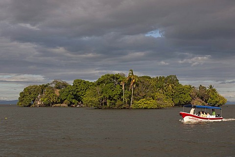 Tourist boat in front of small island with tropical vegetation in Lake Nicaragua, Isletas, Lago de Nicaragua, Nicaragua, Central America