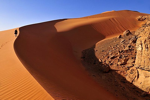 Woman climbing a sanddune at Tin Merzouga, Acacus Mountains or Tadrart Acacus range, Tassili n'Ajjer National Park, Unesco World Heritage Site, Algeria, Sahara, North Africa