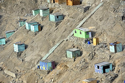 Brightly painted wooden houses built on sandy slopes in the dry desert climate, slums of Amauta, Lima, Peru, South America