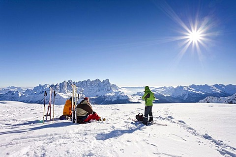 Mountaineers taking a break on the summit of Uribrutto mountain above Passo Valles, Dolomites, Palla group and Passo Rolle mountain at the back, province of Trento, Italy, Europe