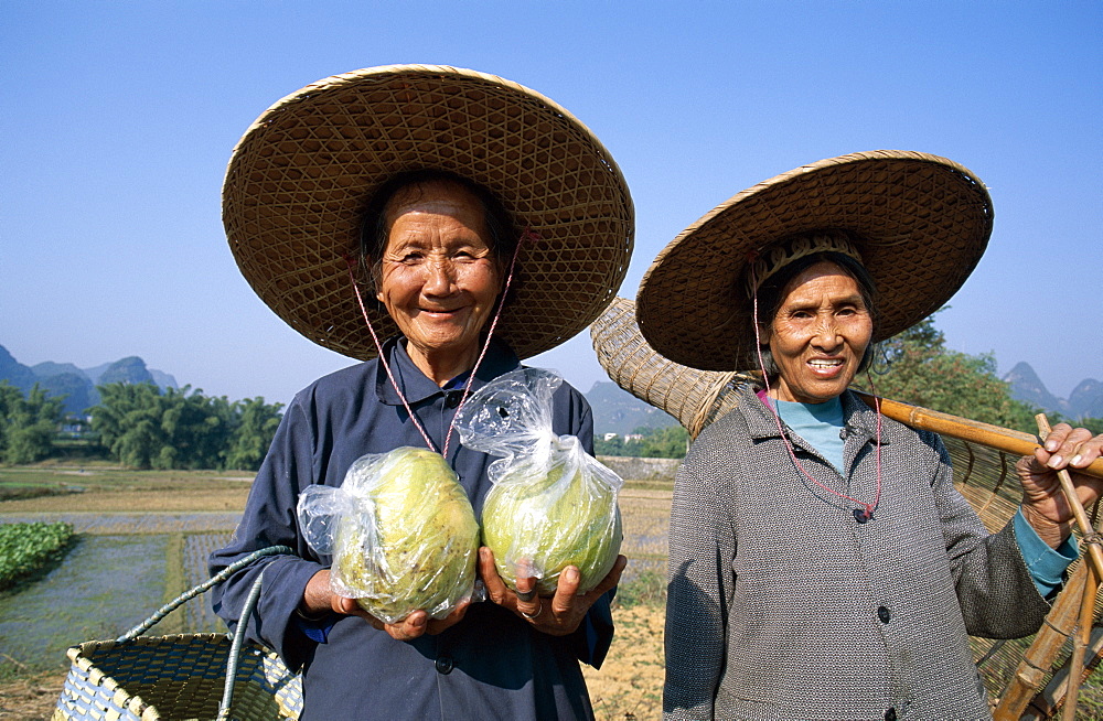 Local women with pomelos and traditional fishing basket, Guilin, Yangshou, Guangxi Province, China, Asia