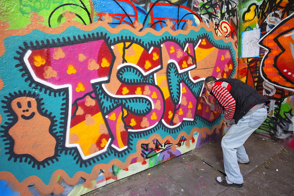 Graffiti artist at work under the Queen Elizabeth Hall, Southbank, London, England, United Kingdom, Europe