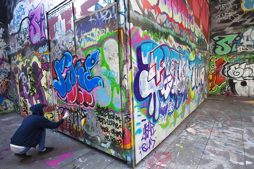 Graffiti artist at work under the Queen Elizabeth Hall, Southbank, London, England, United Kingdom, Europe