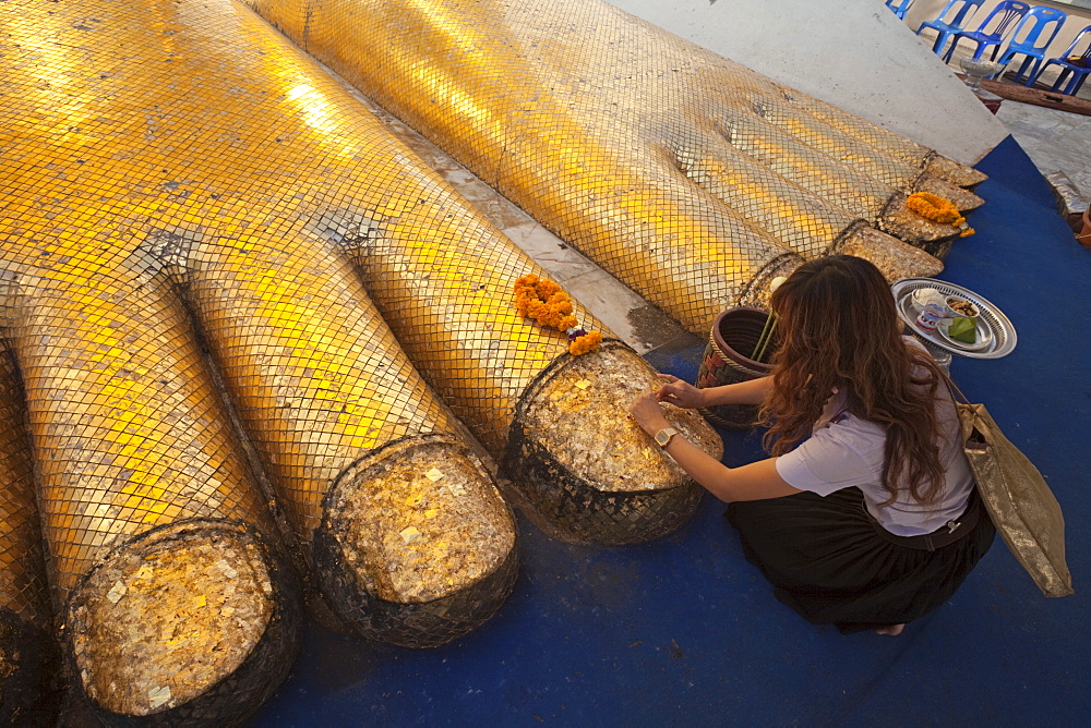 Girl making offerings at foot of the giant Buddha statue in Wat Intharawihan, Bangkok, Thailand, Southeast Asia, Asia