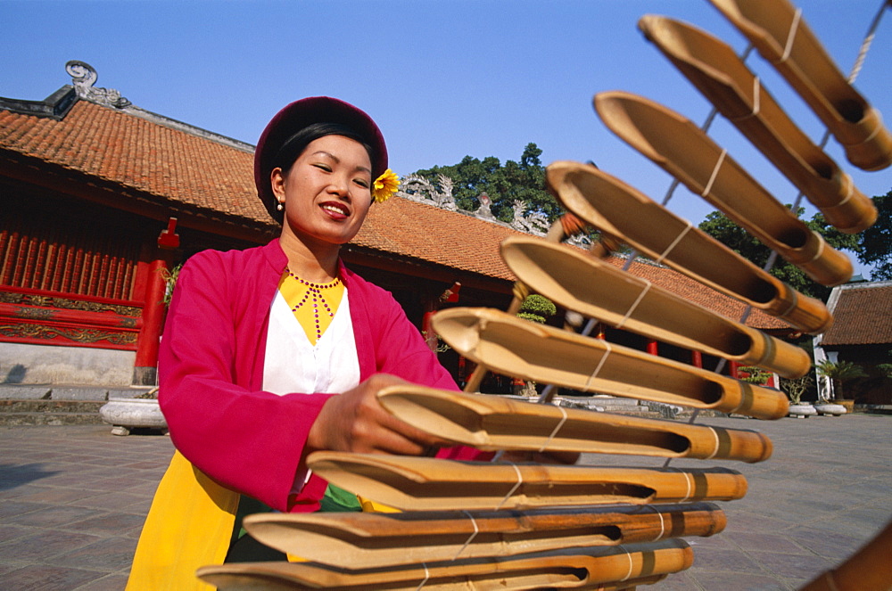 Woman dressed in traditional costume playing a lithophone, a bamboo musical instrument, Temple of Literature, Hanoi, Vietnam, Indochina, Southeast Asia, Asia