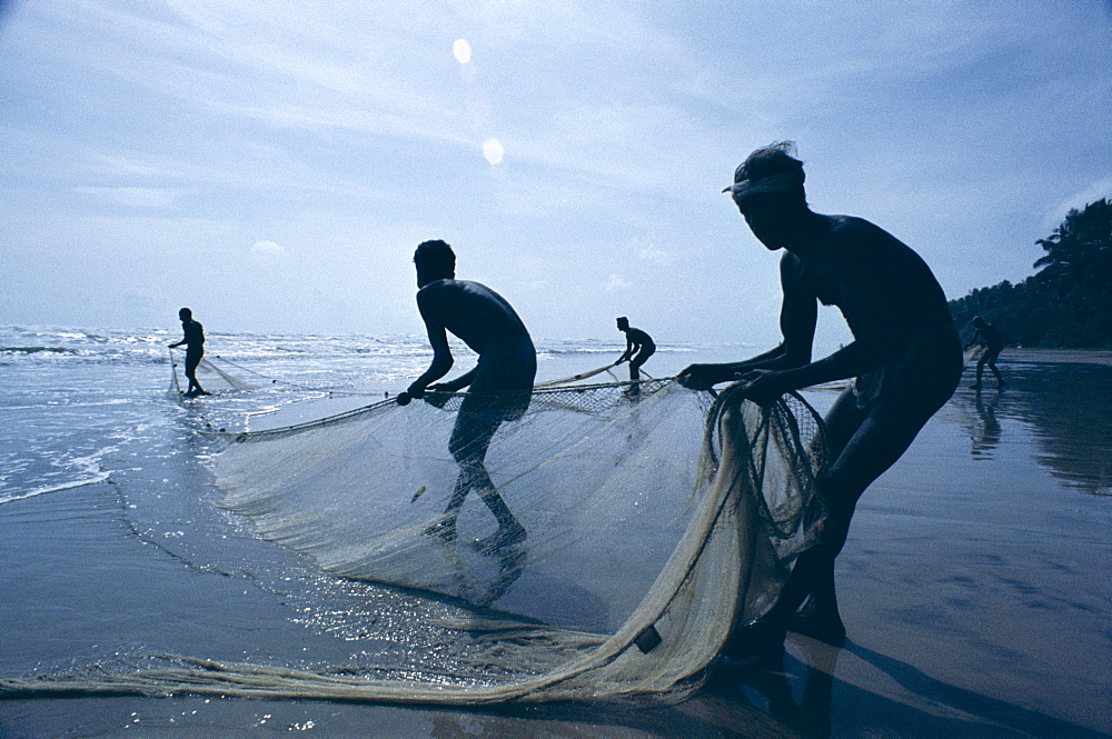 Silhouettes of fishermen pulling in nets, Negombo Beach, Negombo, Sri Lanka, Asia