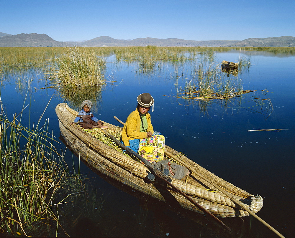 Uros Indian woman and child sitting in traditional reed boat, Lake Titicaca, Peru, South America