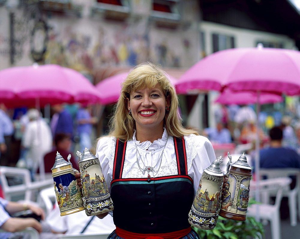 Woman in Baverian costume (Dirndl) holding beer steins, Beer Garden (Biergarten), Mittenwald, Bavaria, Germany, Europe