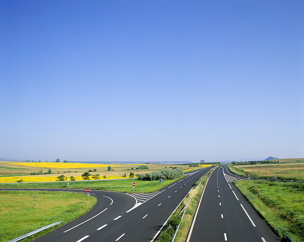 Empty highway with fields of sunflowers in distance, France, Europe