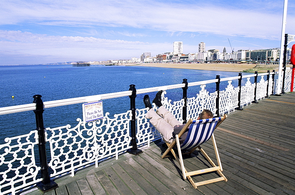 Man resting in deckchair on Brighton Pier, Brighton, Sussex, England, United Kingdom, Europe