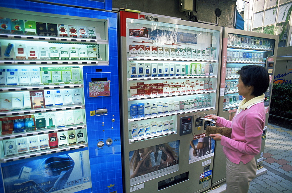 Woman buying cigarettes from vending machine, Tokyo, Honshu, Japan, Asia