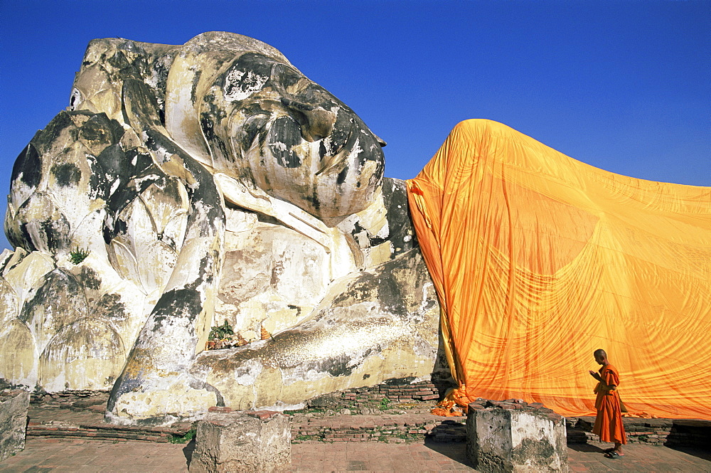 Monk praying at giant reclining Buddha statue, Wat Lokaya Sutha, Ayutthaya Historical Park, Ayutthaya, Thailand, Southeast Asia, Asia