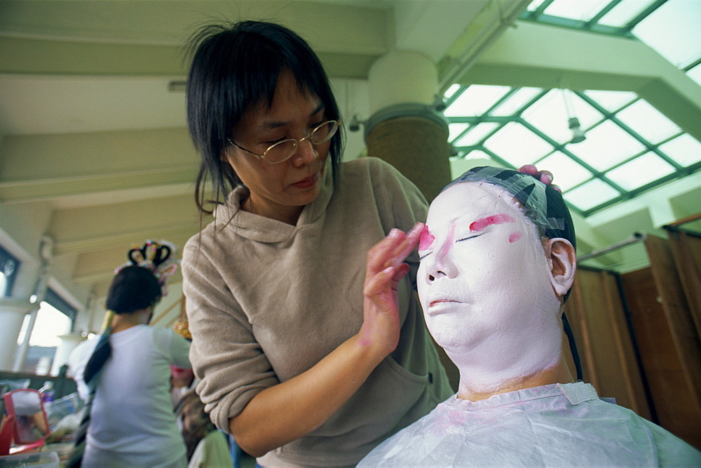 Woman applying make-up to Chinese Opera actor, Hong Kong, China, Asia