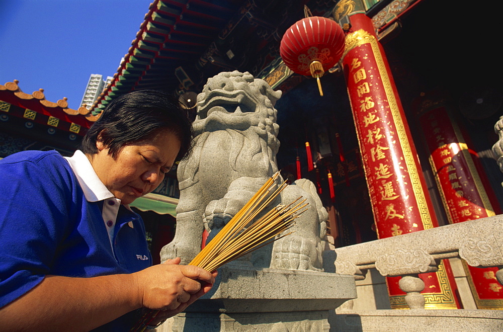 Woman praying with incense sticks, Wong Tai Sin Temple, Wong Tai Sin, Kowloon, Hong Kong, China, Asia