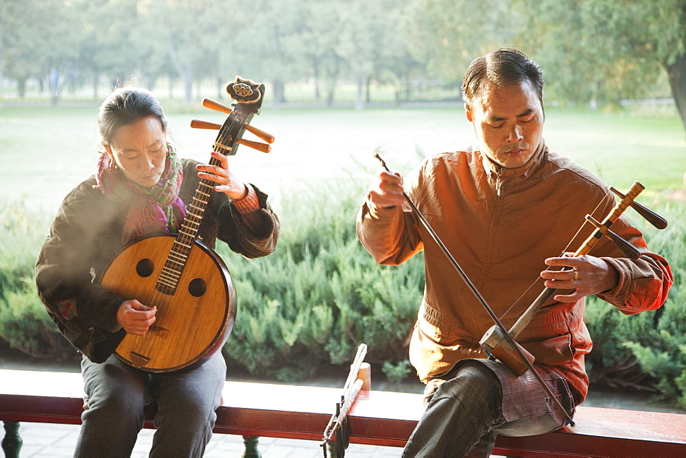 Man and woman playing traditional Chinese stringed instruments, Temple of Heaven Park, Beijing, China, Asia