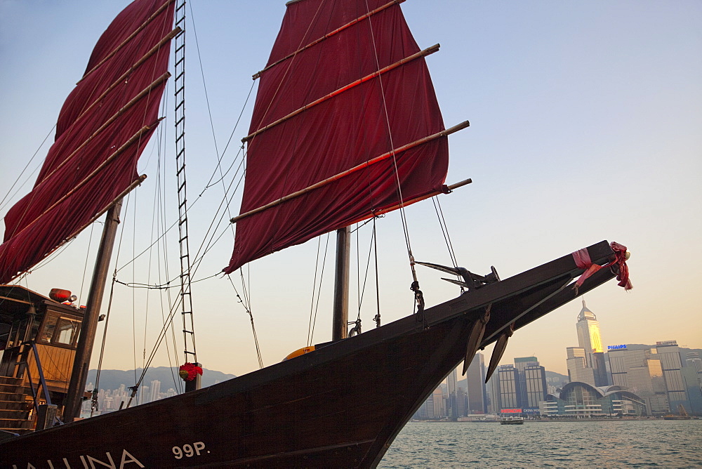 Junk under sail and city skyline in background, Victoria Harbour, Kowloon, Hong Kong, China, Asia