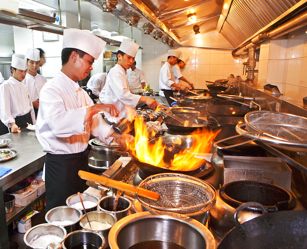 Chefs preparing Chinese cuisine in woks in the modern kitchen of a Chinese restaurant, Beijing, China, Asia