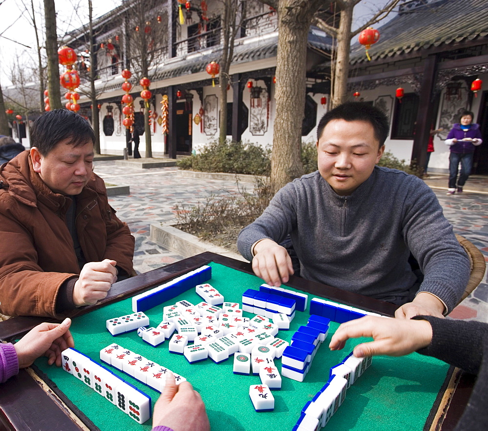 Chinese men playing traditional game of mahjong in a hotel courtyard decorated with red lanterns during Chinese New Year, Chengdu, Sichuan, China, Asia