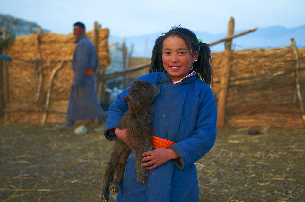 Young Mongolian girl in traditional costume (deel) with her goat, Province of Khovd, Mongolia, Central Asia, Asia