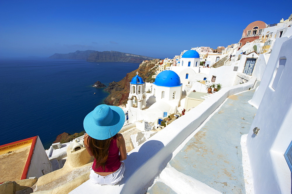 Tourist and church with blue dome, Oia (Ia) village, Santorini, Cyclades, Greek Islands, Greece, Europe