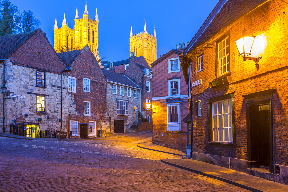 View of illuminated Lincoln Cathedral viewed from the cobbled Steep Hill at dusk, Lincoln, Lincolnshire, England, United Kingdom, Europe